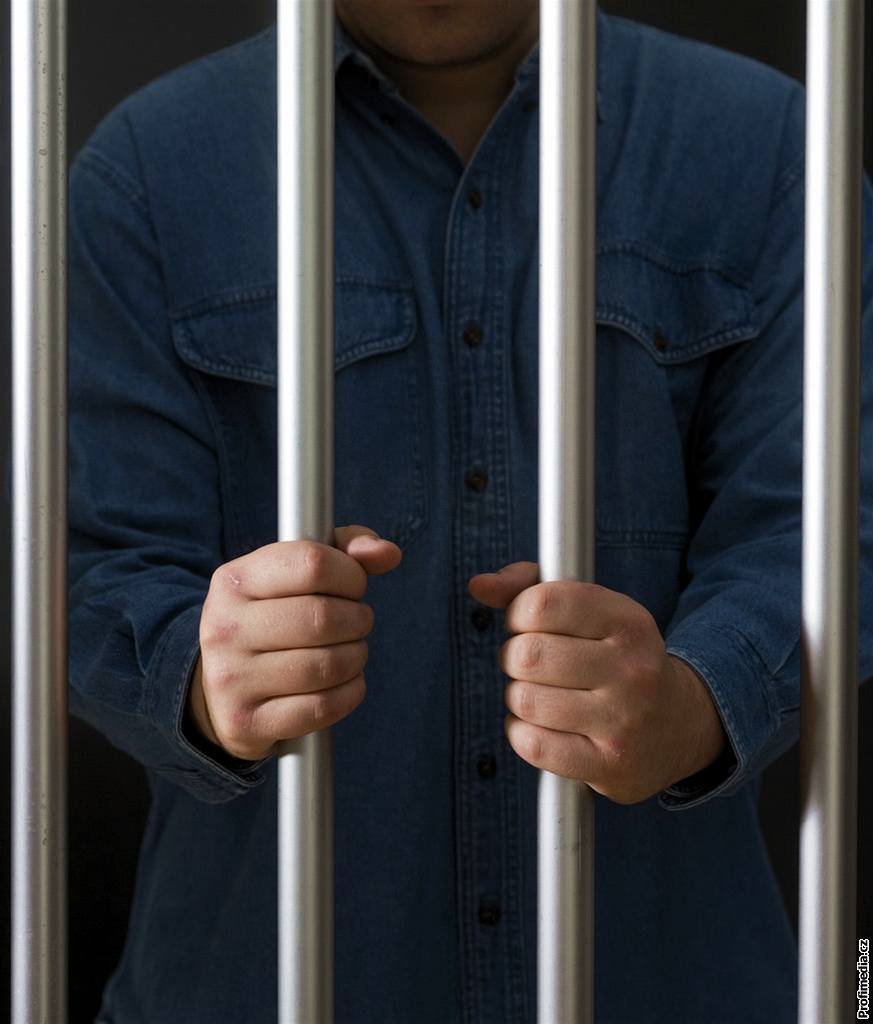 A person standing behind jail bars