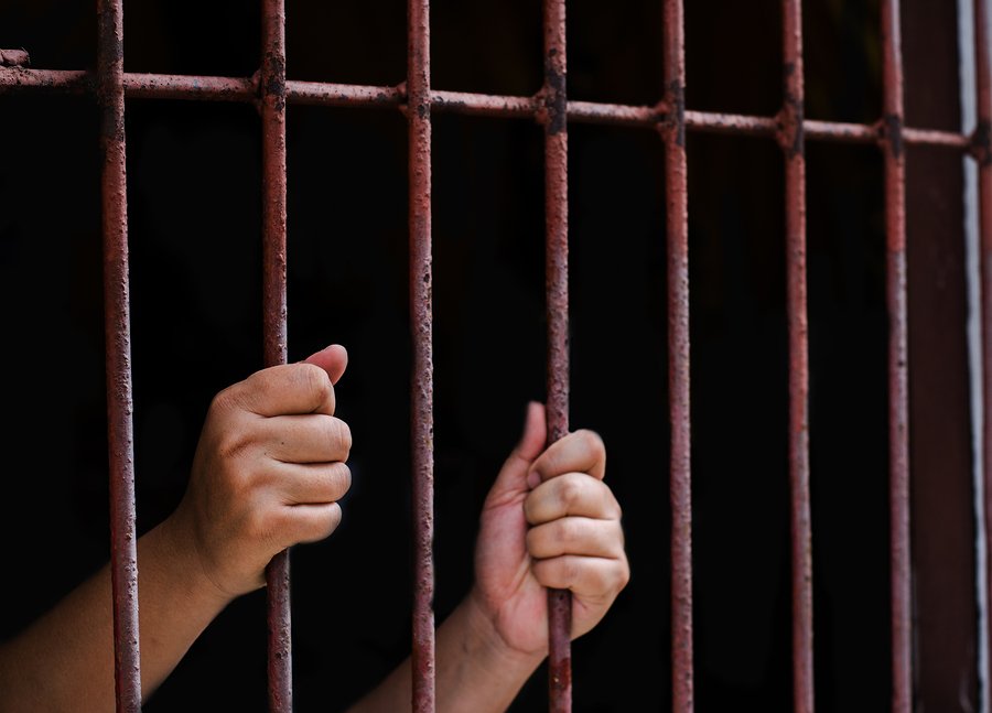 hands grip jail bars